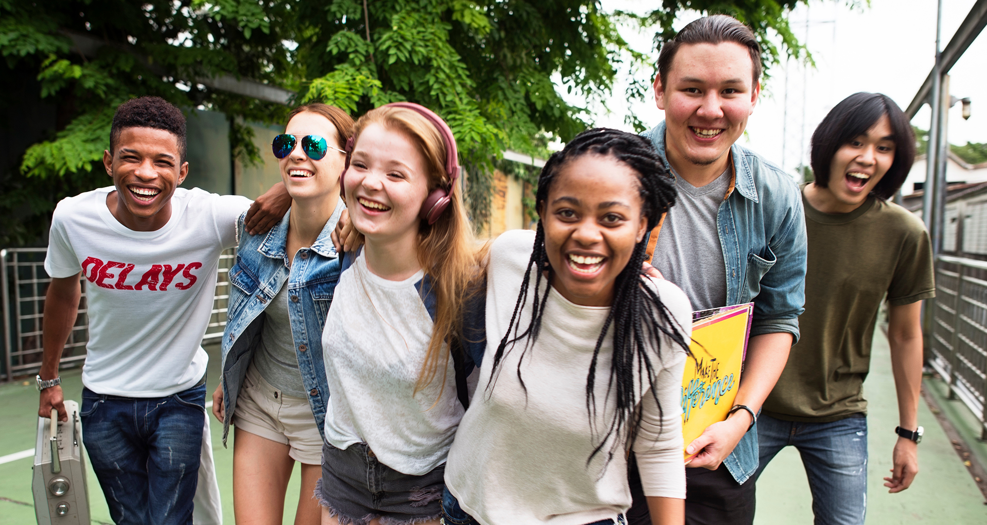 A diverse group of teenagers walking together and smiling at the camera.