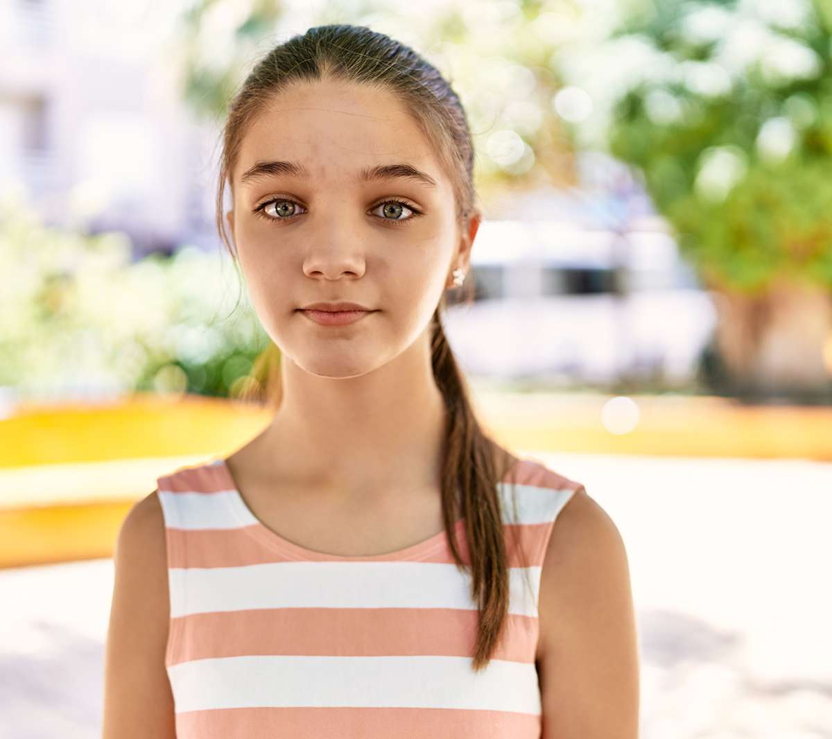 A young girl staring into the camera. Her face looks serious, but happy.