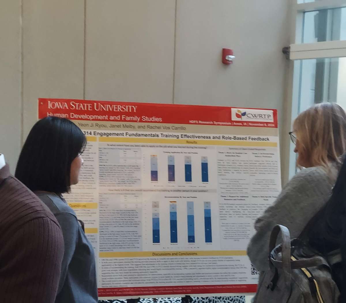 Soyoung Park standing next to her poster, presenting it to a faculty member standing on the other side.