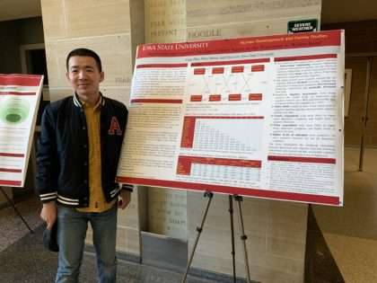 Feng Zhao stands beside his research poster