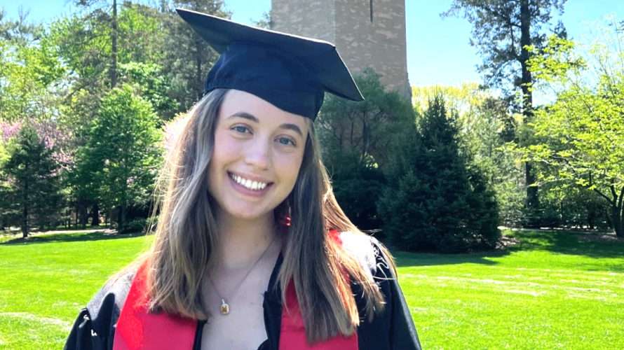 Madeline Robinson posing in her graduation cap and gown in front of the Campanlie on ISU campus