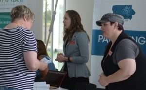 Two PIAL staff speaking with conference goers at a booth.